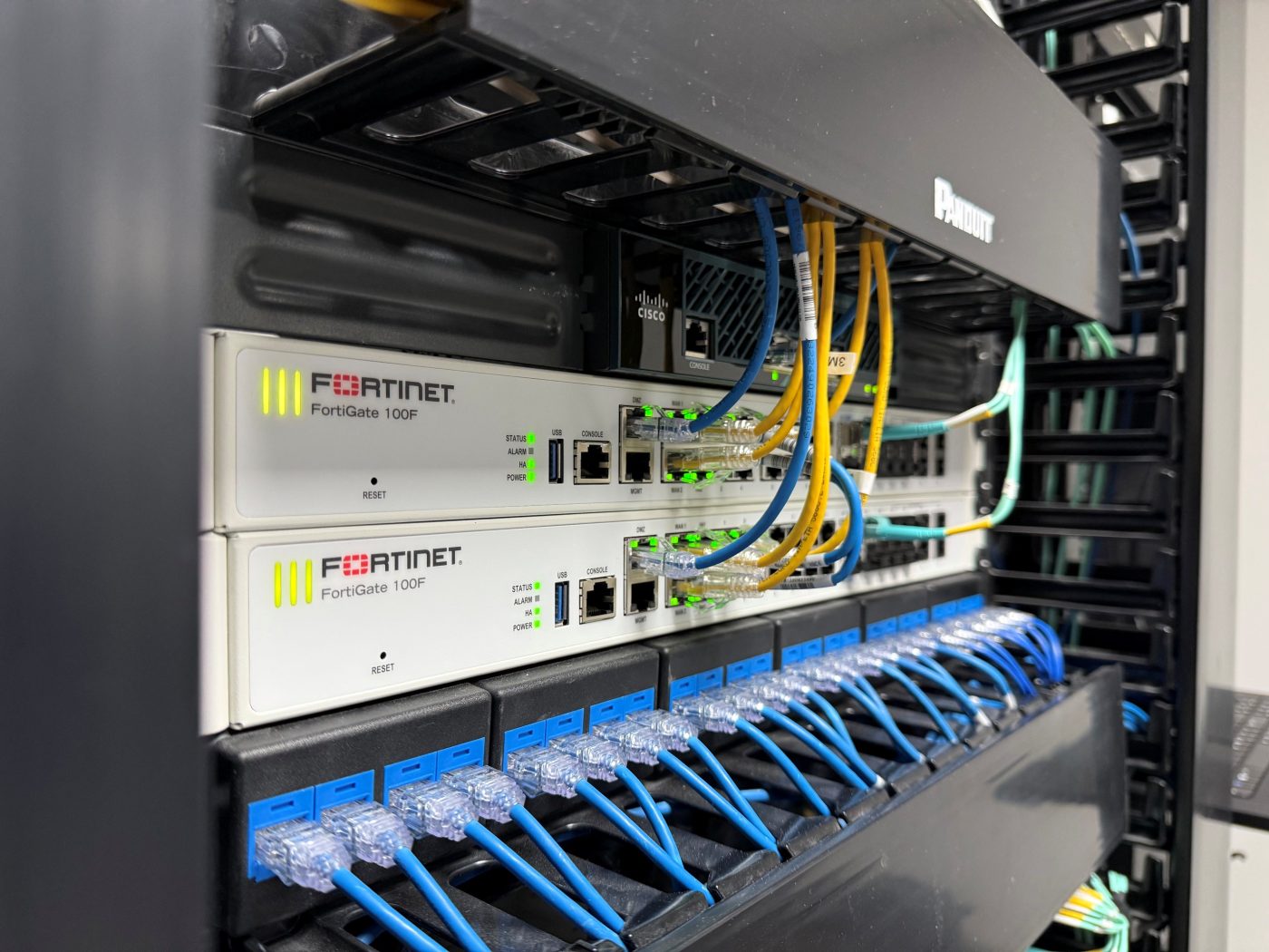 Par de firewalls Fortinet FortiGate 100F en alta disponibilidad dentro del rack de IT Experts de México, con switch Cisco, patch panel y organizadores Panduit.