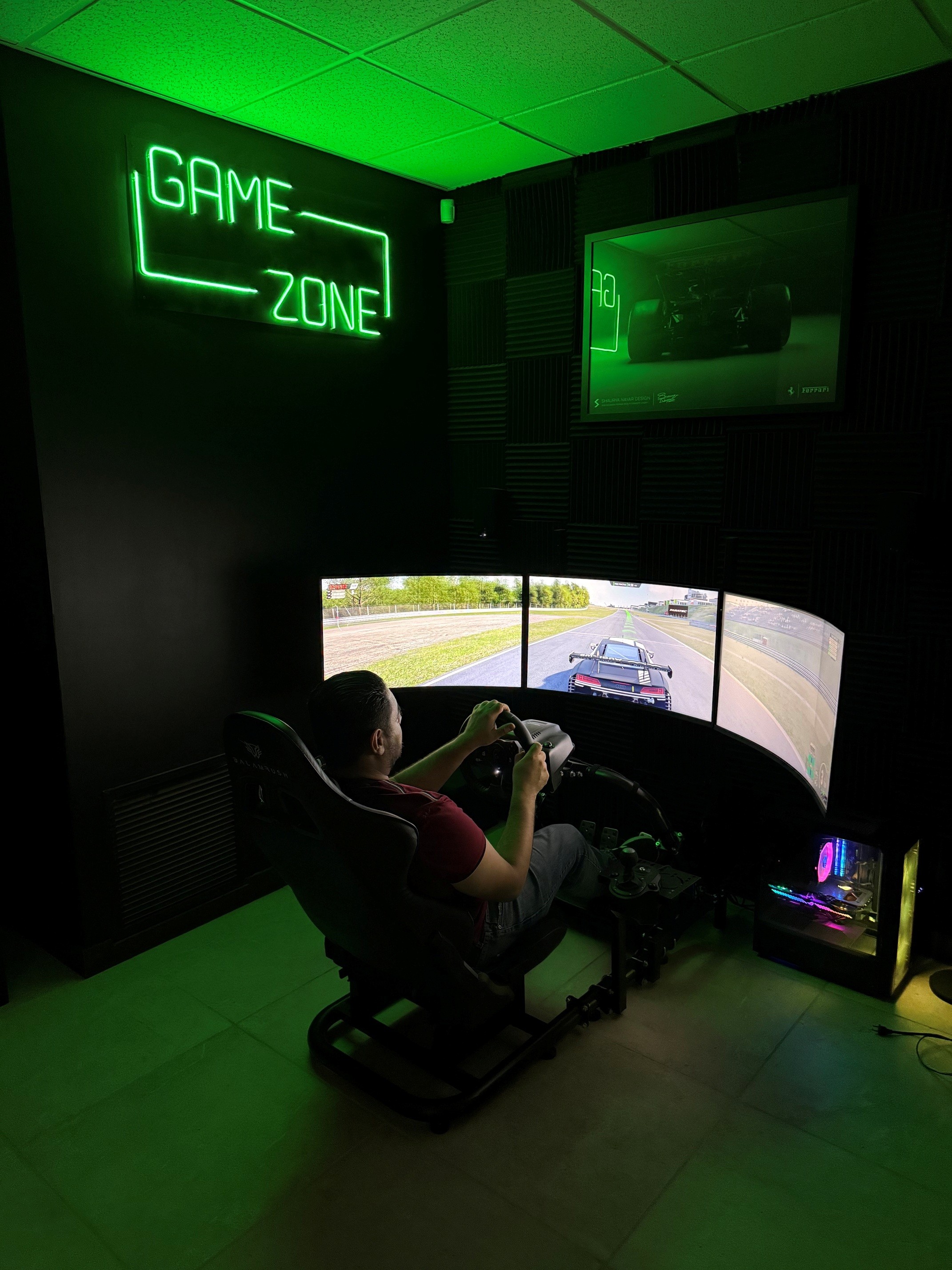 Racing rig de tres pantallas en la game zone, con letrero de neón